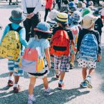Children in summer clothes with back packs walking.